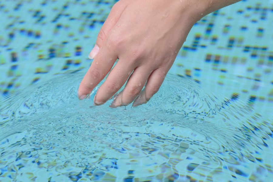 chica tocando agua de piscina con la mano