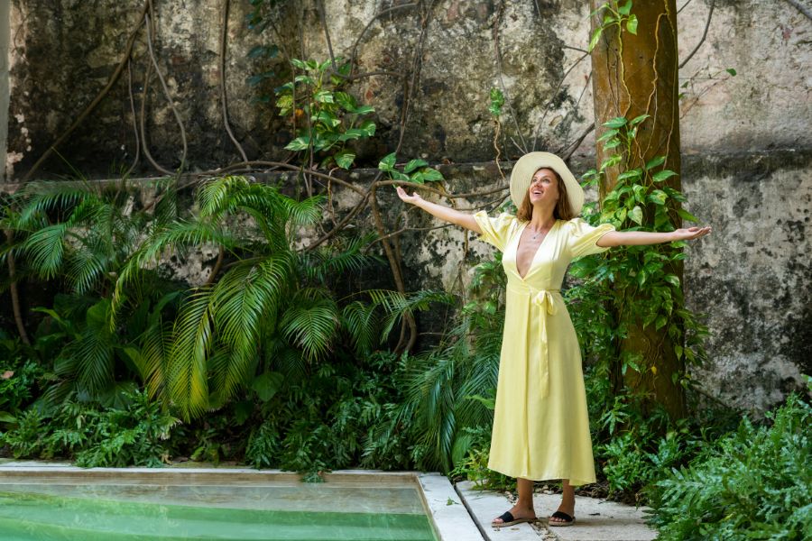 chica abre sus brazos frente a su jardín con piscina