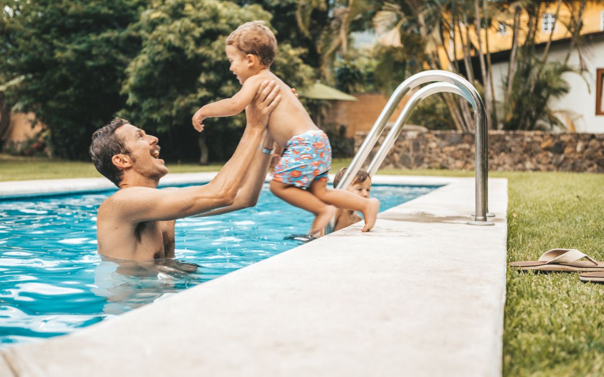niño se tira a la piscina con su padre en una piscina que ha instalado clorador salino